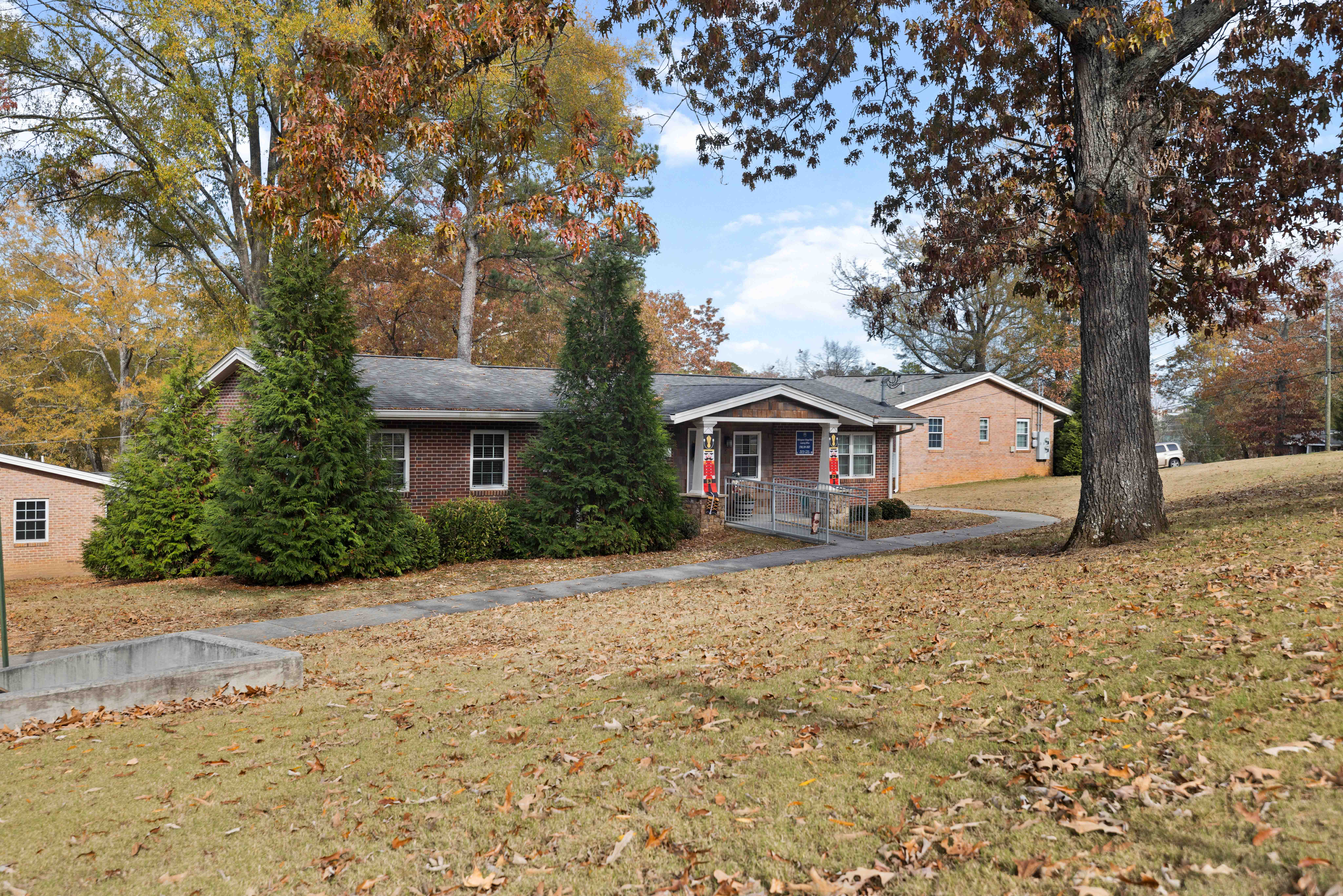 A house with a red door is surrounded by trees with yellow leaves.